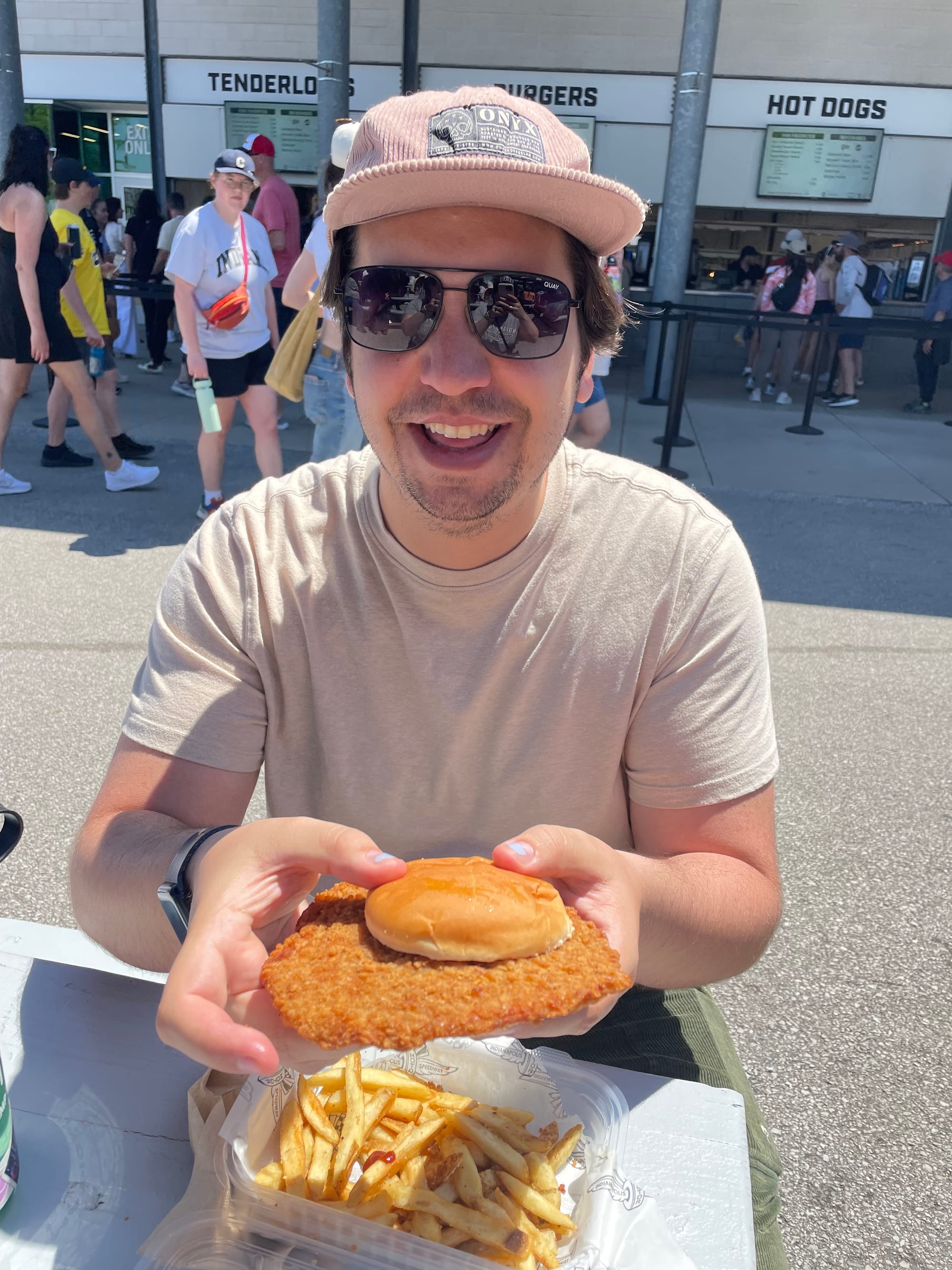 A picture of Michael Zarick holding a pork tenderloin sandwhich that overflows out of the bun it's contained in.